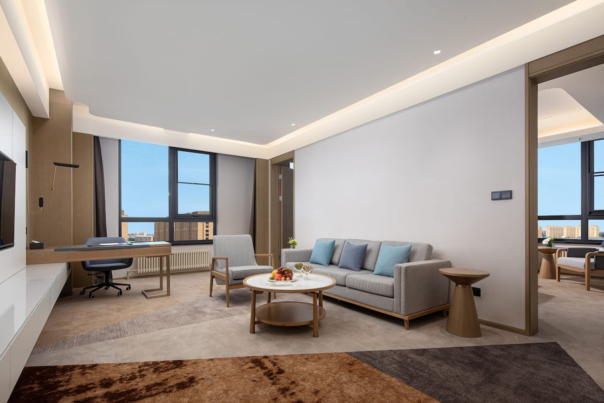 A modern living room with a grey sofa, a round coffee table, and a desk with a chair.