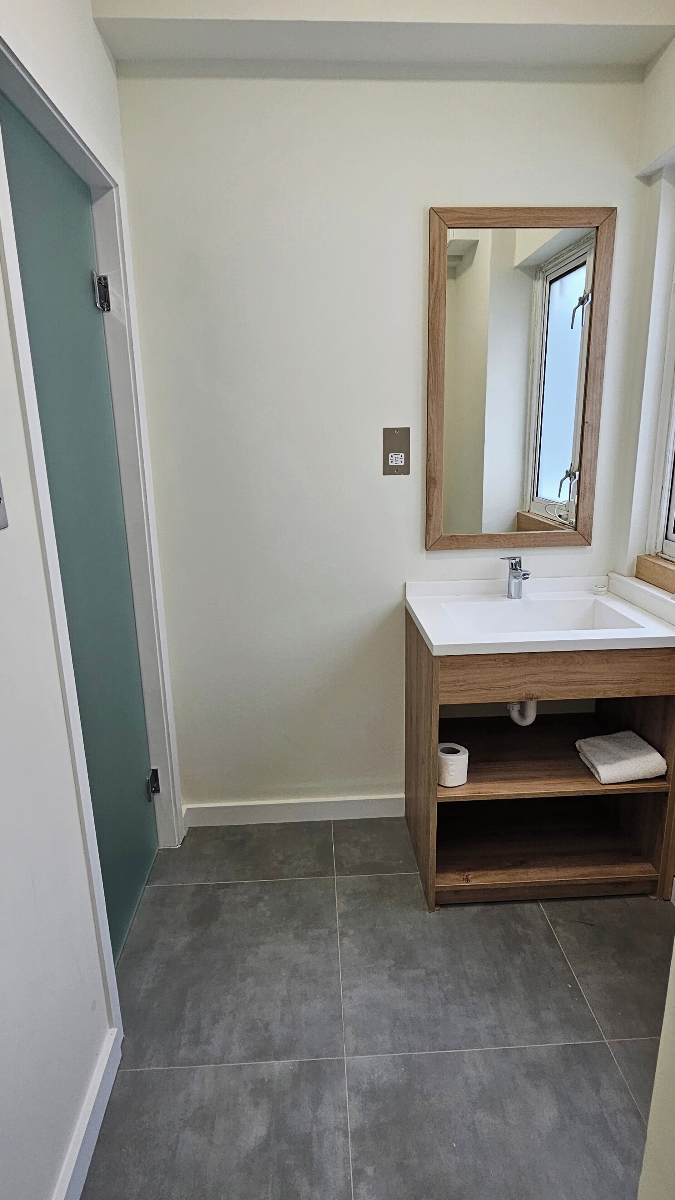 A bathroom with a white sink, wooden vanity, and a mirror.