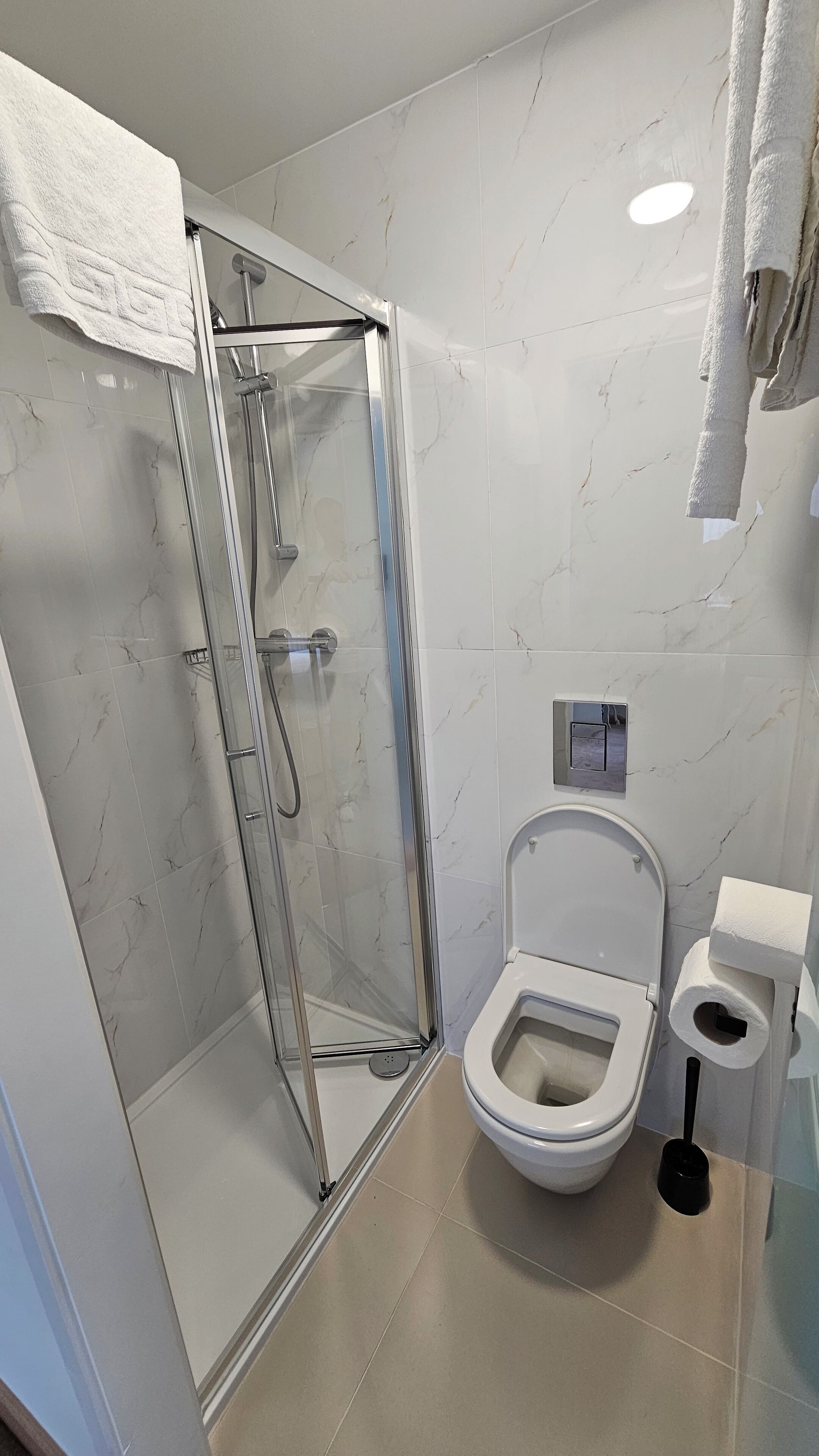 A bathroom with a glass-enclosed shower, a toilet, and a bidet.