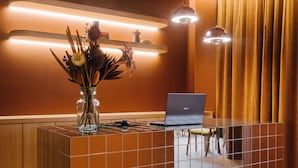 Een receptiebalie met een laptop, een vaas met bloemen en hanglampen.