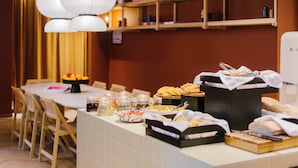 Een buffetopstelling met diverse gerechten en een eetgedeelte met stoelen en een tafel.