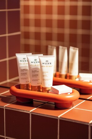 A bathroom with toiletries including face and body cleansing gel, shampoo, and body wash.