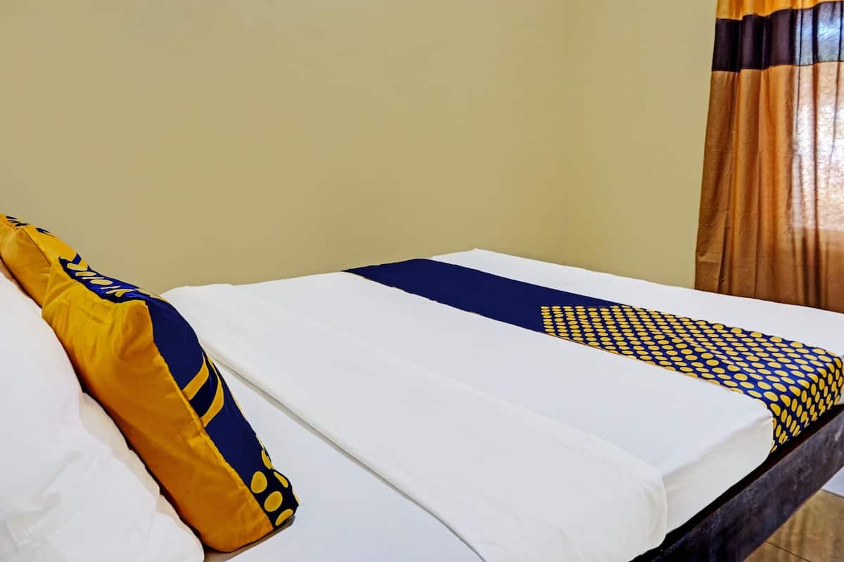 A bed with white sheets, a blue and yellow pillow, and a patterned bedspread.