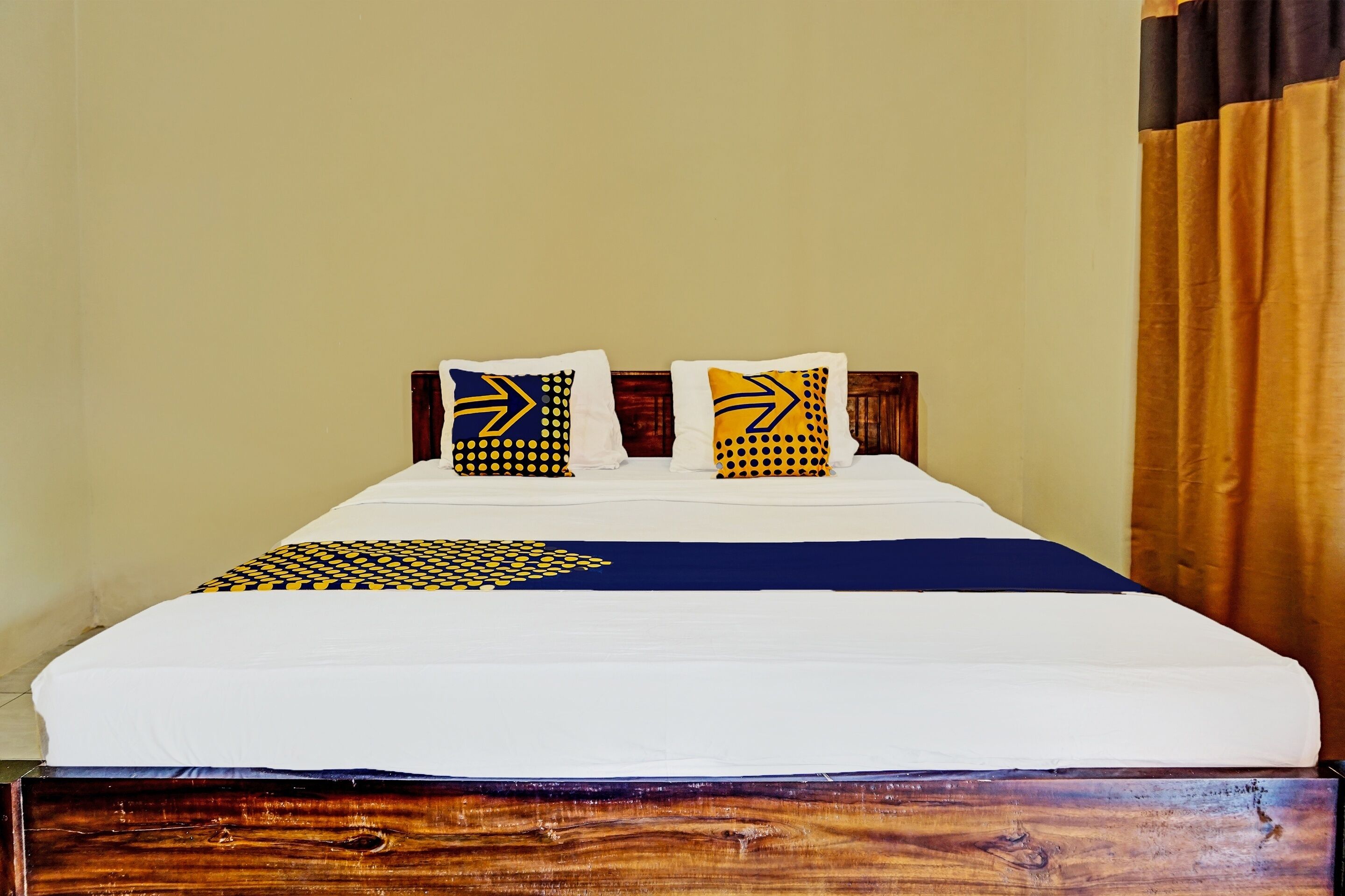 A bed with a white mattress and two pillows with geometric patterns.