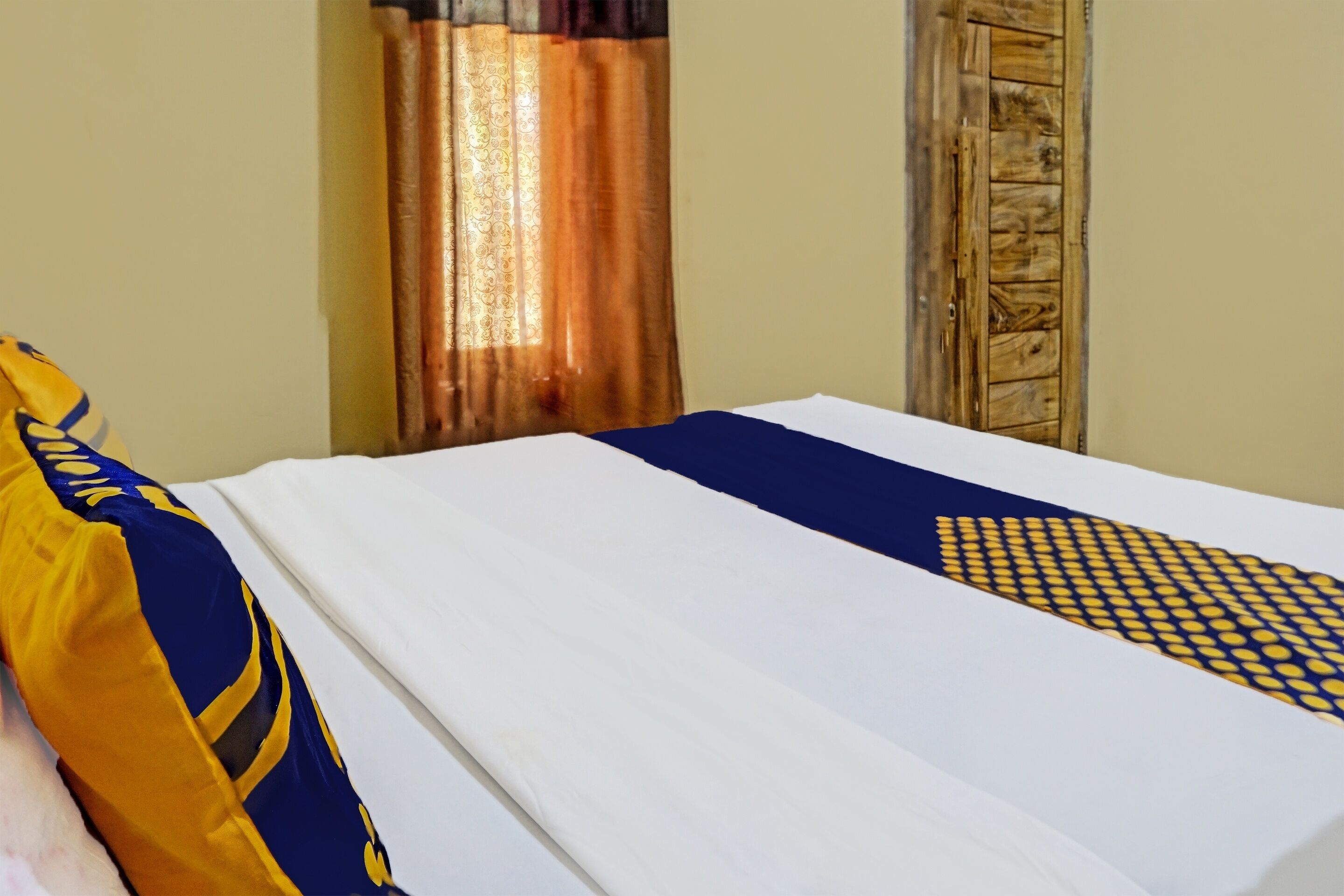 A neatly made bed with a white and blue bedspread, a decorative pillow, and a patterned pillow.