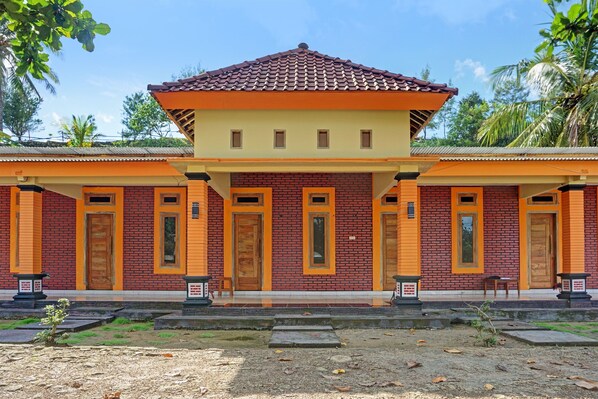 Un bâtiment à deux étages, doté d’une façade en briques rouges et de touches de couleur jaune, et comportant de nombreuses portes et fenêtres.