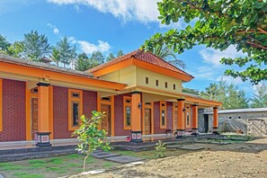 A two-story building with a red and yellow facade, multiple doors, and a covered porch area. - OYO Life 91988 Azka Homestay Klayar (Sendang)