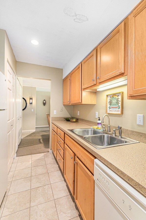A kitchen with wooden cabinets, a dishwasher, and a sink.