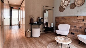 Una sala de estar moderna con suelo de madera, un sillón blanco, una mesa de centro redonda de madera, una consola negra con un espejo y un panel de madera montado en la pared.