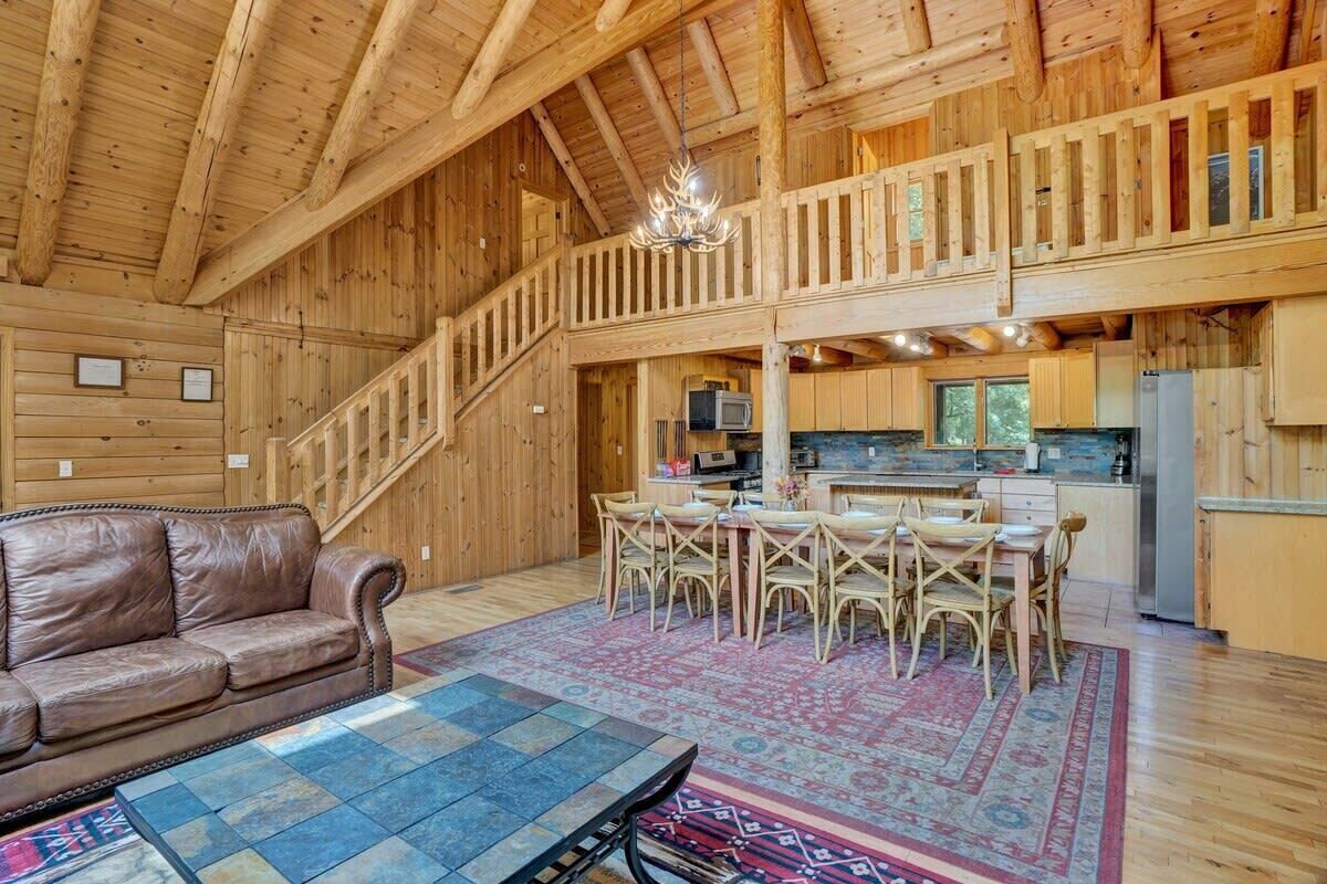 A spacious wooden interior with a dining area, kitchen, and a staircase leading to an upper level.