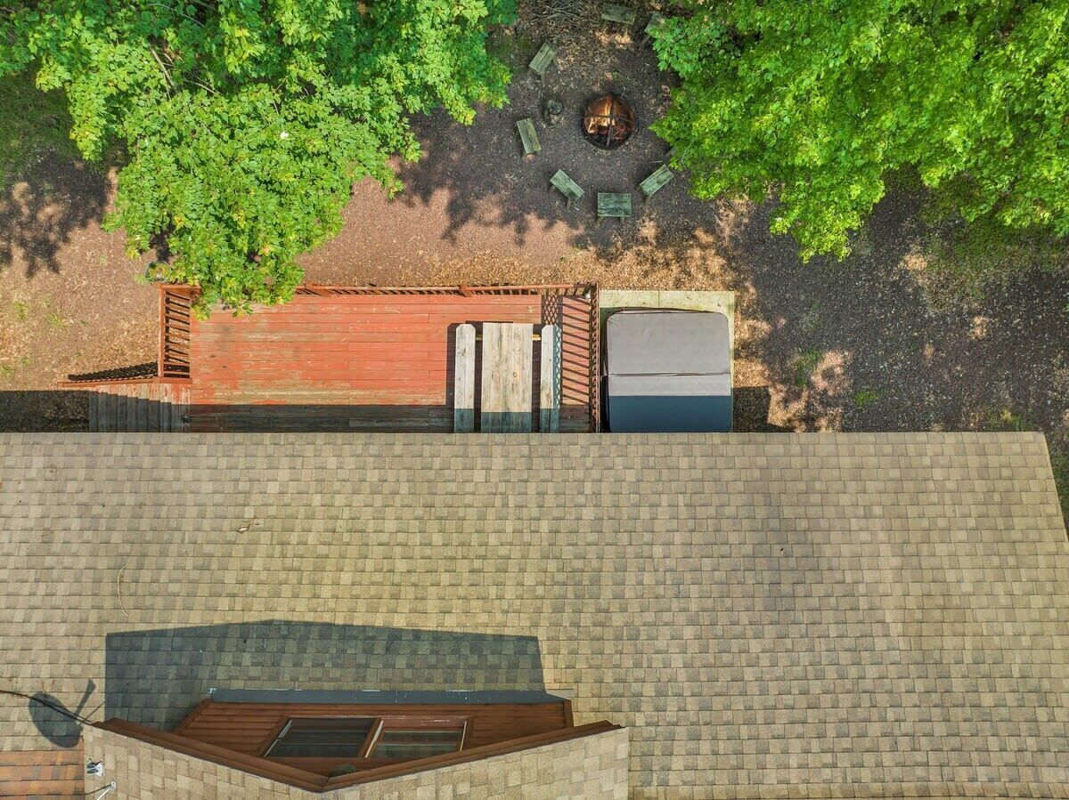 Vista aérea de una azotea con un brasero, una terraza de madera y un muro de ladrillo.