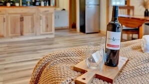 Eine moderne Küche mit Essbereich, einer Weinflasche und einem Glas auf einem Holzuntersetzer.