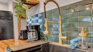 A kitchen with a black sink, wooden countertop, and a green tiled backsplash. - Elements Pocono Cabin | Pickleball | Firepits (Barrett Township)