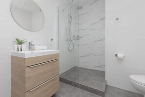 A modern bathroom with a wooden vanity, a glass shower enclosure, and a toilet. - Sunny Studio in Warsaw | Balcony and Private Parking (Warszawa)