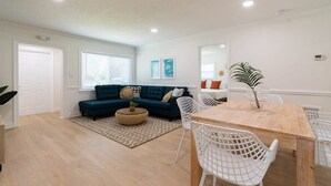 A living room with a sofa, a coffee table, and a dining table with chairs. - The Juni-7 Unit Renovated Complex (Cocoa Beach)