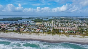 An aerial view of a coastal town with a beach, residential areas, and a water body.