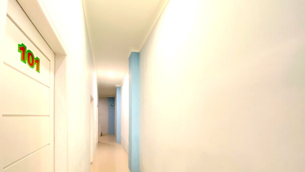 Een gang met een deur waarop '101' staat en een blauwe muur.