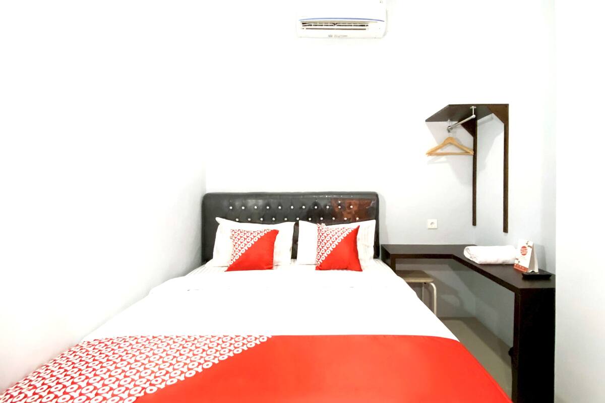 Une chambre d’hôtel équipée d’un lit, d’une table de chevet, d’un miroir et d’un climatiseur fixé au mur.
