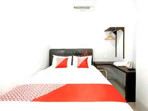 Une chambre d’hôtel équipée d’un lit, d’une table de chevet, d’un miroir et d’un climatiseur fixé au mur.