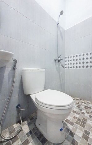 Une salle de bain avec des toilettes, une douche et un sol carrelé.