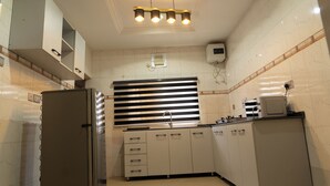 Een moderne keuken met witte kasten, een ingebouwde kookplaat en een raam met horizontale zonwering.