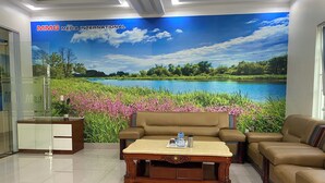 A modern lobby with a large mural of a lake and greenery, a reception desk, and comfortable seating areas. -  MMG GLOBAL Apartments (Hai Phong)