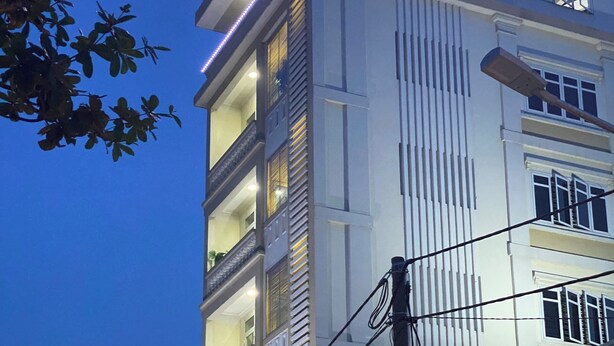 A multi-story building with a prominent sign at the top, balconies on each floor, and a ground-level entrance with a covered area. -  MMG GLOBAL Apartments (Hai Phong)