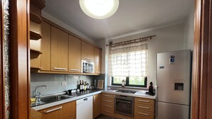 Eine Küche mit Holzausstattung, einer eingebauten Mikrowelle, einem Kühlschrank und einem Fenster mit Vorhang.