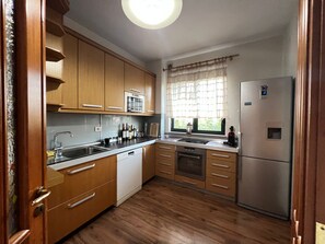 Eine Küche mit Holzausstattung, einer eingebauten Mikrowelle, einem Kühlschrank und einem Fenster mit Vorhang.
