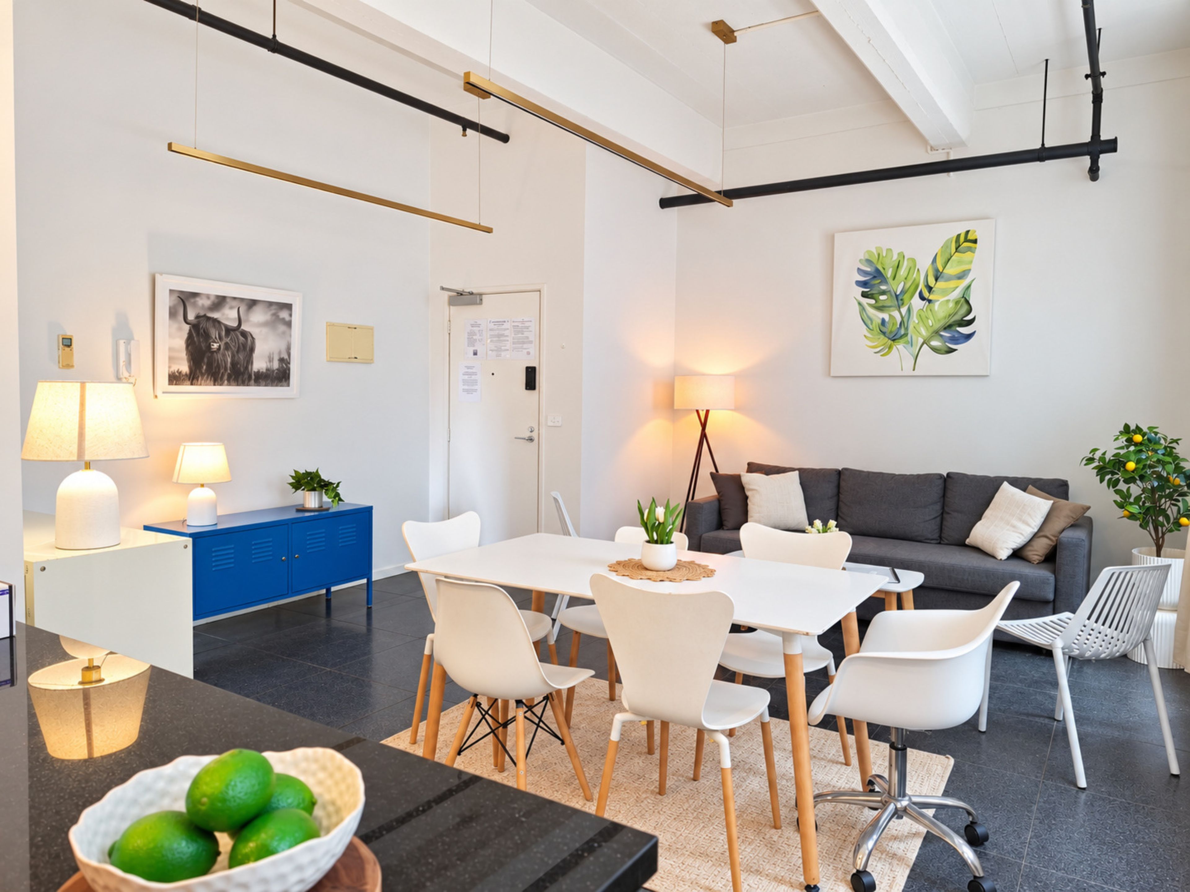 A modern living room with a dining area, featuring a sofa, chairs, a table, and a coffee table.