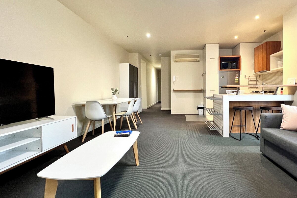 A modern apartment with a living room, dining area, kitchenette, and a small bar area.