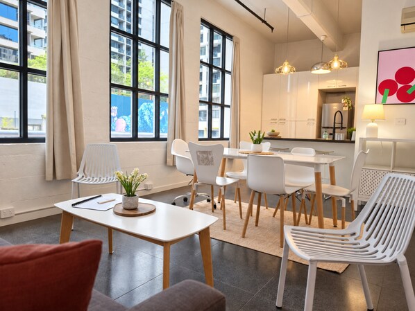 A modern interior with a dining area, kitchen, and large windows.