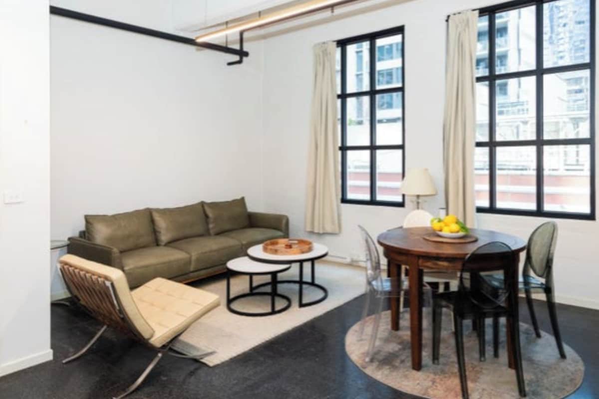 A modern living room with a sofa, a small round table, and a dining table with chairs.