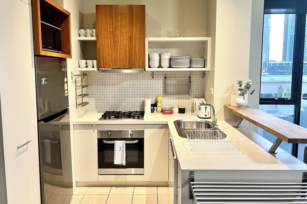 A modern kitchen with a built-in oven, stainless steel sink, and a window with a city view.