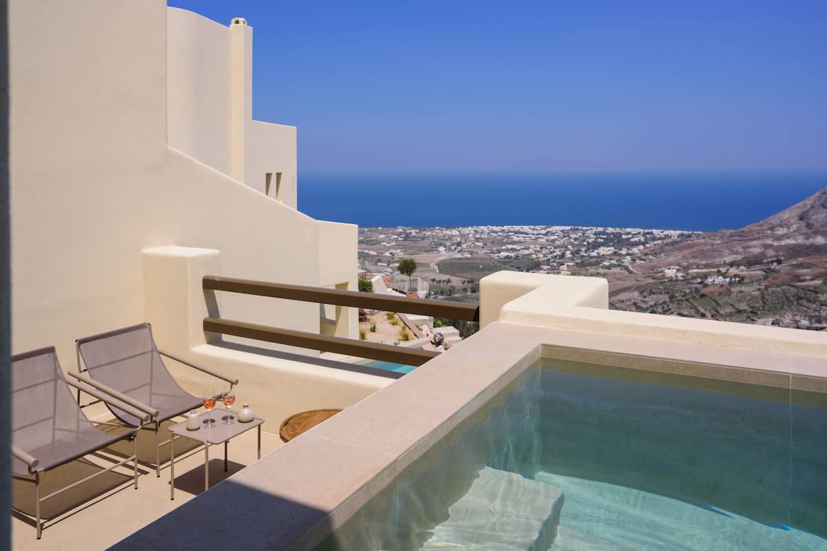 A poolside area with a clear view of the sea and a distant town.