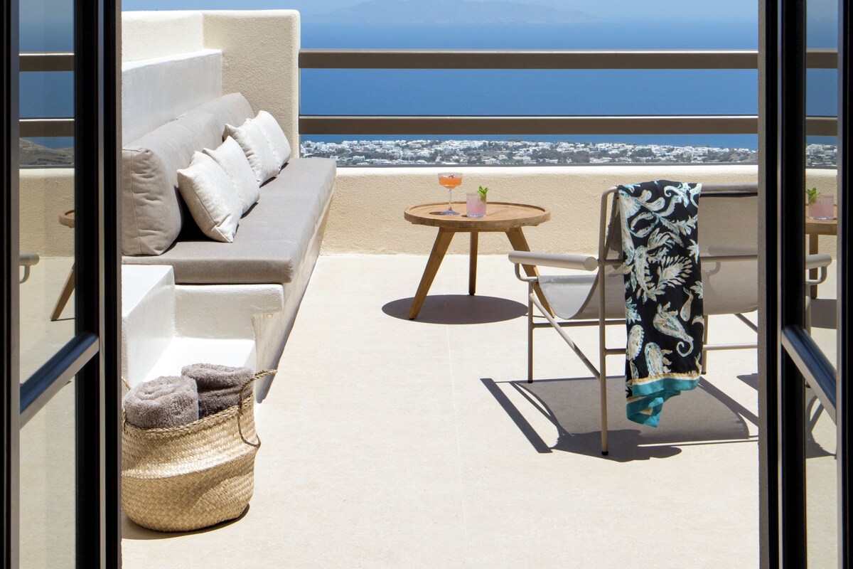 A balcony with a sofa, a chair, a small table, and a hanging chair.