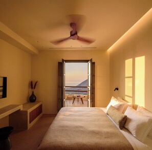 Ein Schlafzimmer mit Bett, Schreibtisch, Stuhl und Meerblick.