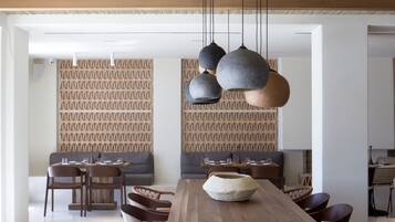 A modern dining area with a wooden table, wicker chairs, and pendant lighting.
