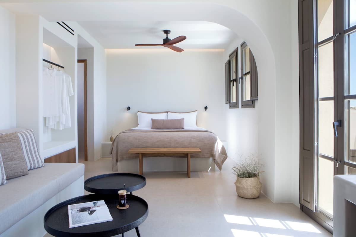 A modern bedroom with a bed, a bench, a coffee table, and a window.