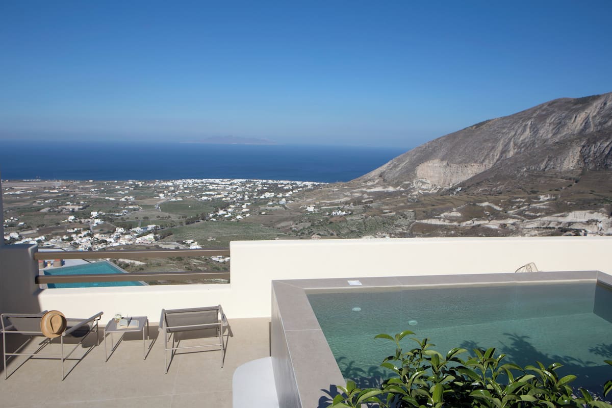 A rooftop pool with a view of the ocean and a town below.