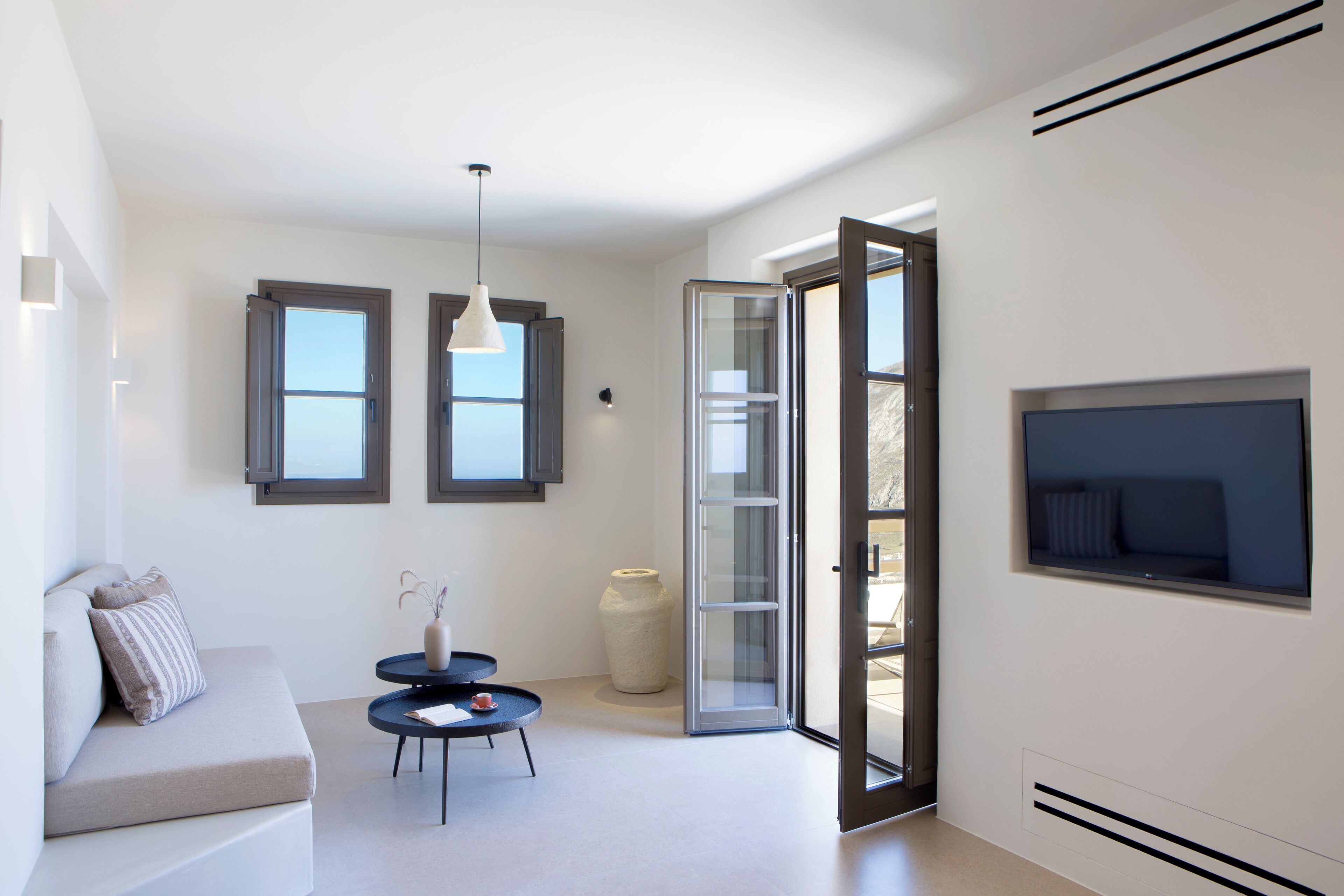 A modern living room with a sofa, a small round table, and a TV mounted on the wall.