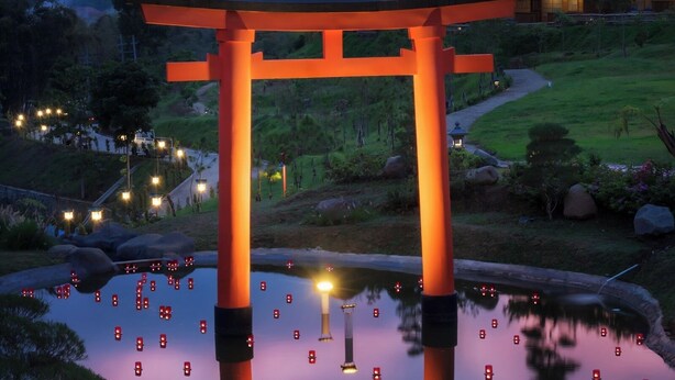 A traditional Japanese torii gate in a serene garden setting with a pond reflecting the gate and lights. - The Onsen Hot Spring Resort (Batu)