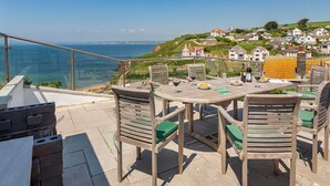 En terrasse med et bord og stole med udsigt over kysten.