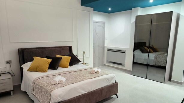 Un dormitorio moderno con una cama grande, mesitas de noche, un armario y un espejo.