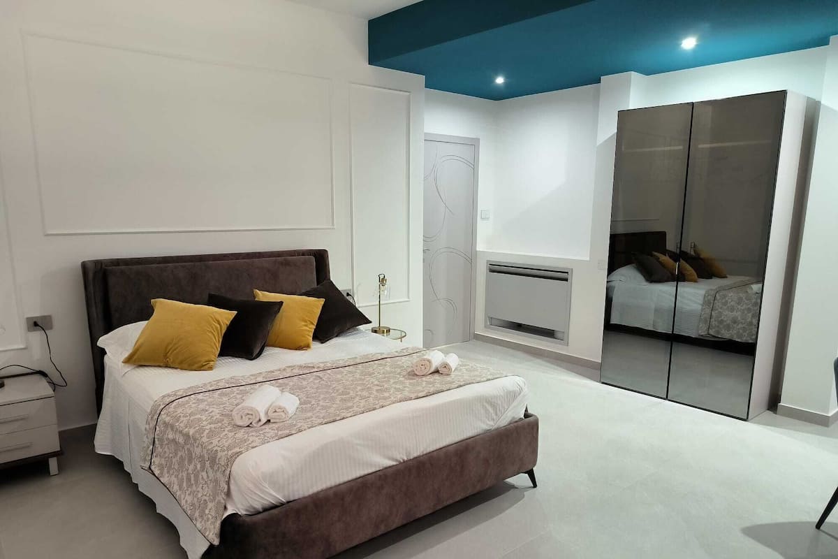Un dormitorio moderno con una cama grande, mesitas de noche, un armario y un espejo.