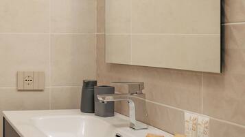 A modern bathroom with a white sink, a large mirror, and a towel rack.