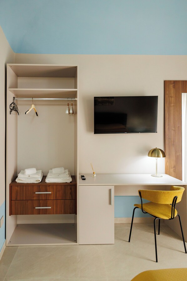 Une petite pièce comprenant un bureau, une chaise, un téléviseur et une armoire.