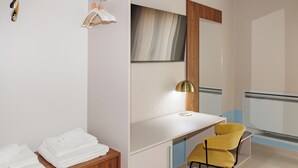 Una habitación de hotel con un tocador de madera, un escritorio blanco, una silla amarilla y un espejo grande.
