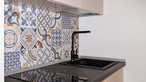 Una cocina con un lavamanos moderno, un salpicadero con azulejos coloridos y una encimera elegante.