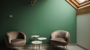 Una habitación con dos sillones cómodos, una mesita y una lámpara fijada a la pared.
